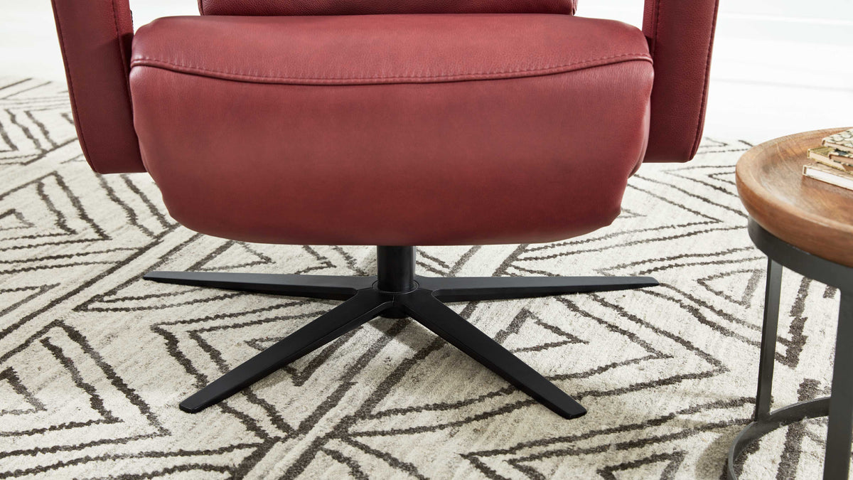 Nahaufnahme des HUKLA® | IL Sessels, Interliving Serie 4541, Leder, mit Sternfuß, neben einem runden Tisch auf einem gemusterten Teppich.