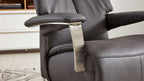 Dunkelgrauer Leder-Sesselsitz mit gepolstertem Armteil und gebürstetem Metallarmstütze, im Hintergrund weiße Kommode und Teppich.