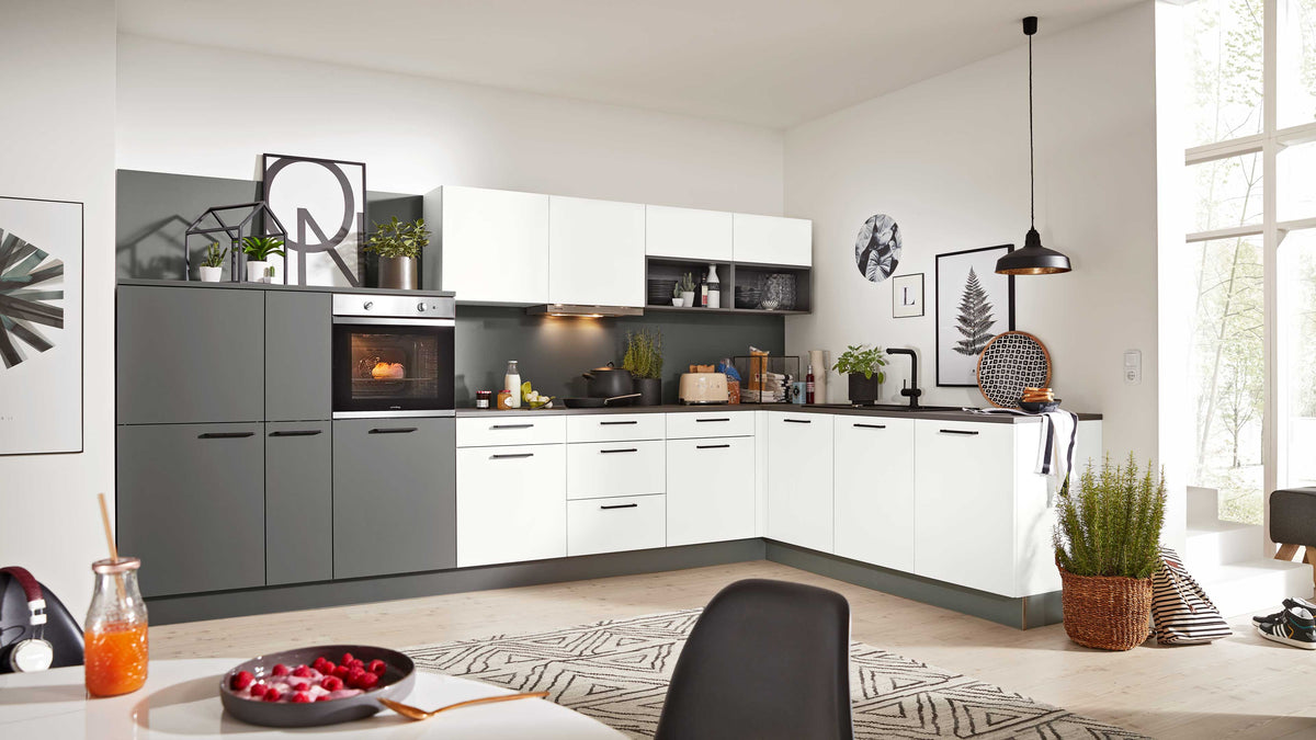 Moderne Küchenzeile in L-Form mit grauen und weißen Fronten, Backofen, Pflanzen und dekorativen Bildern an der Wand.