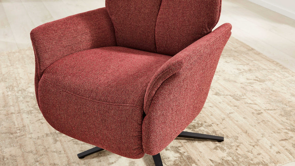 Roter, gepolsterter Lounge-Sessel mit strukturierter Stoffoberfläche und schwarzem Drehsternfuß auf hellem Teppichboden.