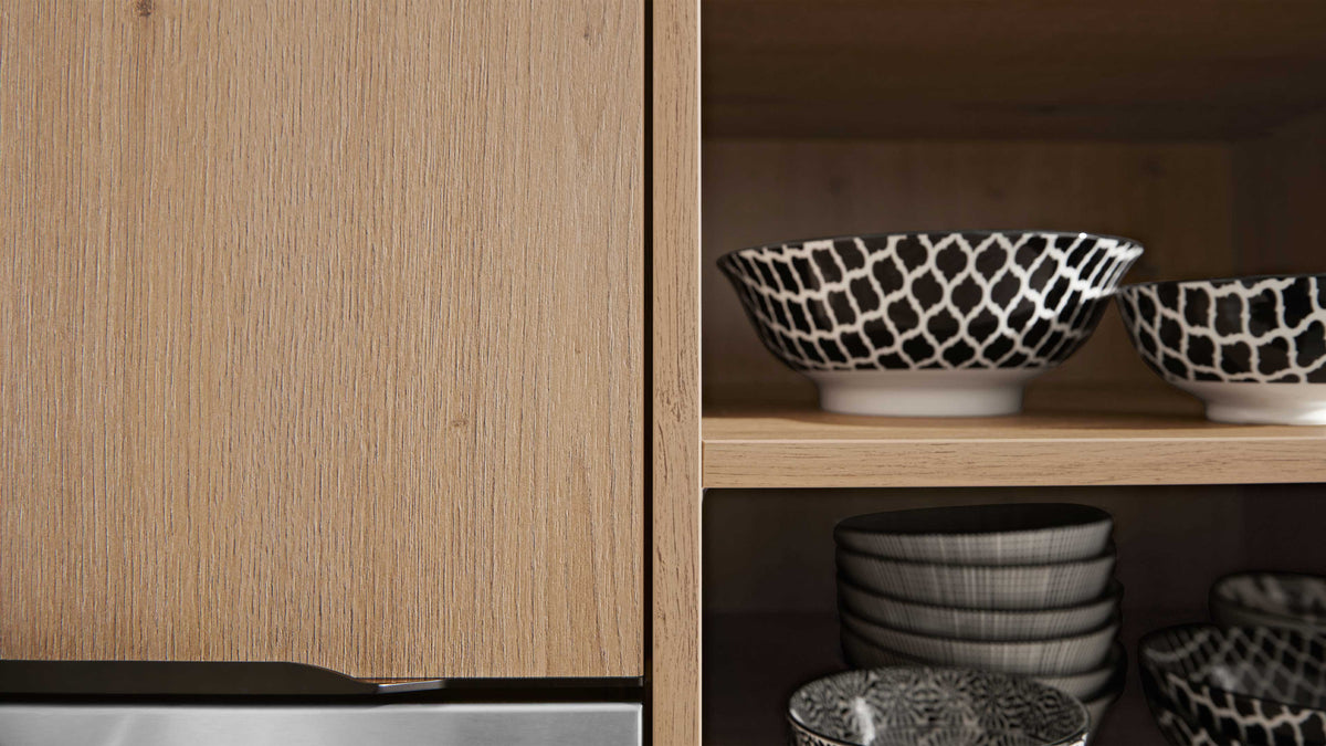 Helle Holzschrankfront links, rechts offene Regalfächer mit schwarz-weiß gemusterten Schalen und gestapelten Tellern.