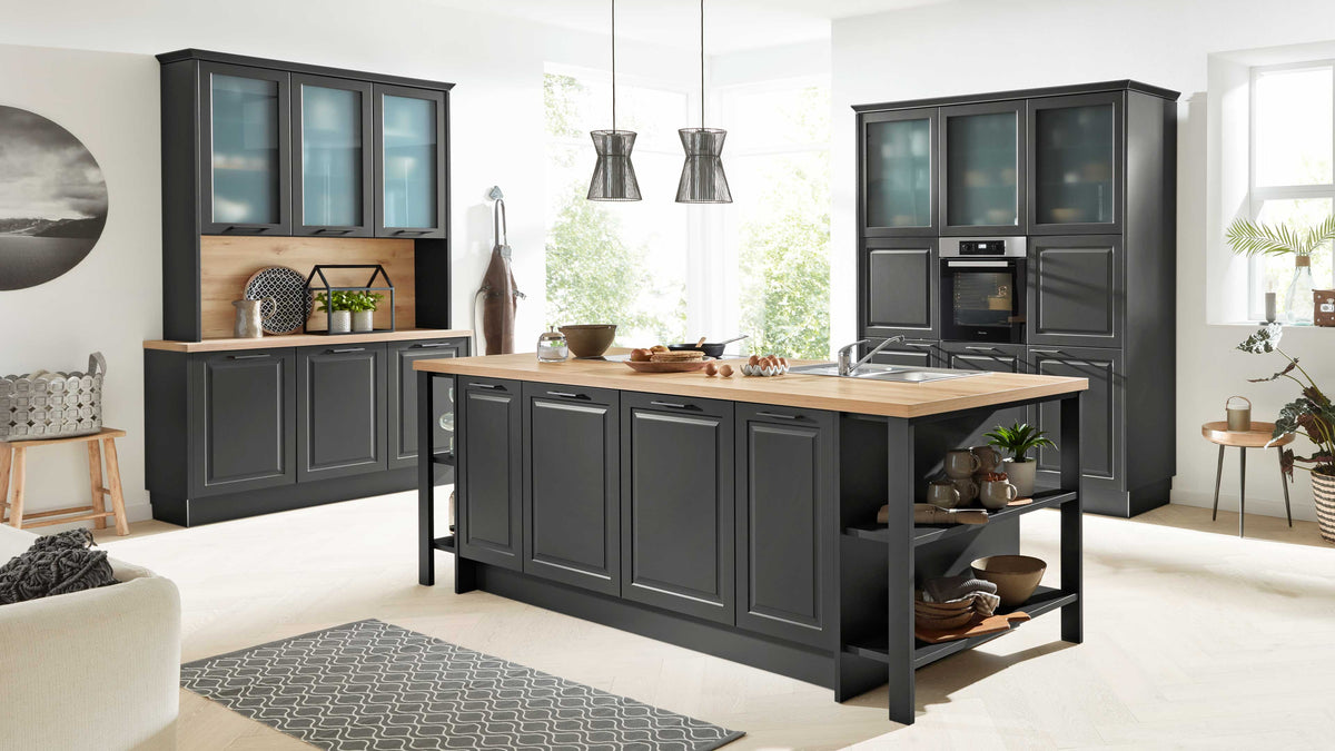 Die moderne Küche verfügt über eine große Insel mit Holzoberfläche, schwarze Fronten, einen Herd mit Backofen und hängende Lampen.
