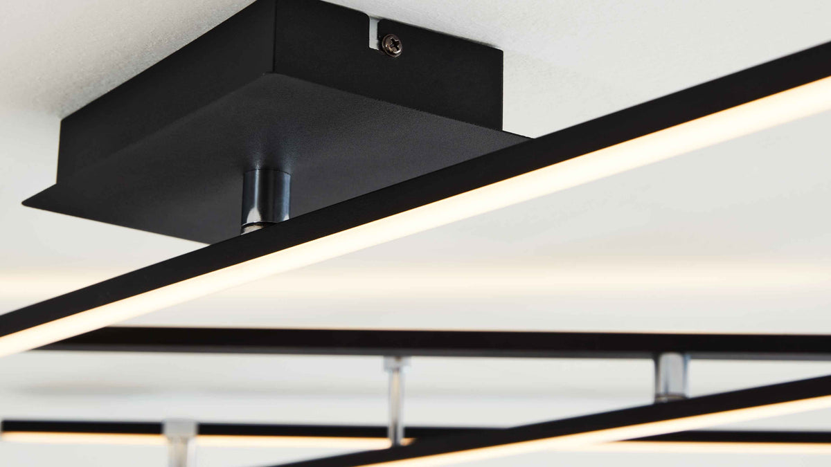Schwarze, rechteckige Deckenbefestigung mit quer verlaufenden, leuchtenden LED-Stangen und sichtbaren chromfarbenen Haltern an weißer Decke.