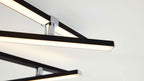 Deckenleuchte mit mehreren schwarzen, rechteckigen Leuchtstangen mit weißer Lichtdiffusorfläche und glänzenden Chromverbindern.