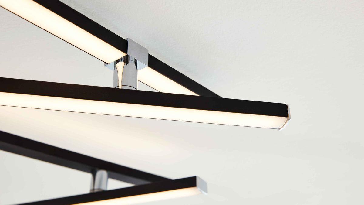 Deckenleuchte mit mehreren schwarzen, rechteckigen Leuchtstangen mit weißer Lichtdiffusorfläche und glänzenden Chromverbindern.