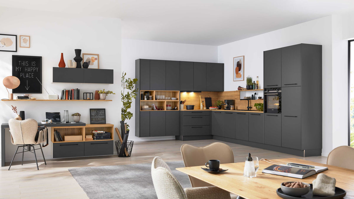 Eine moderne Küche in dunklem Grau mit Holzelementen, einem Esstisch und dekorativen Regalen im Hintergrund.