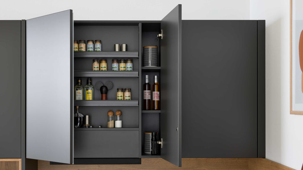 Geöffneter dunkelgrauer Küchenschrank mit Regalen, bestückt mit Gewürzgläsern, Ölflaschen, Salz- und Pfefferstreuern und Tellern.