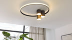 Deckeuchte mit einem großen leuchtenden Ring und drei schwarzen zylindrischen Downlights, die warmes Licht nach unten werfen.