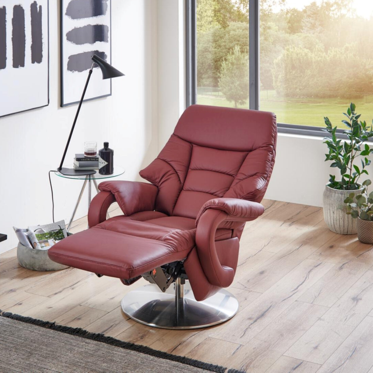 Ein Relaxsessel von Steinpol Polsteria mit verlängerter Fußstütze steht in einem modernen Wohnzimmer in der Nähe von Fenstern und üppigen Pflanzen.