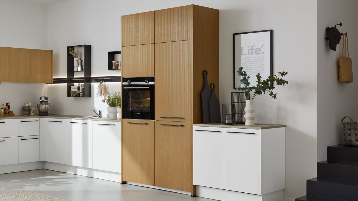 Hochschrank mit vertikal geriffelter Holzfront und eingebautem schwarzen Ofen, seitlich weiße Unterschränke und Arbeitsplatte.