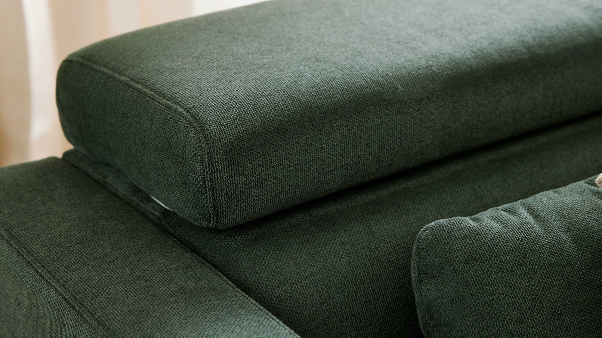 Nahaufnahme eines dunkelgrünen Sofas mit grob gewebtem Bezugsstoff, sichtbaren Nähten und gestapelten Rücken- und Sitzpolstern.