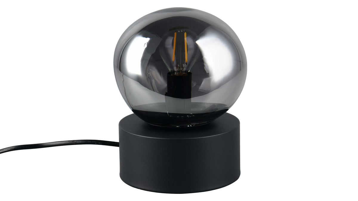 Tischlampe mit rundem, rauchgrauem Glaskugel-Schirm, sichtbarer Filament-Glühbirne und zylindrischem schwarzem Sockel, mit schwarzem Kabel.
