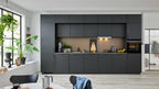 Moderne Einbauküche in dunkler Holzoptik mit einer Arbeitsplatte, einem Herd, einer Spüle und einem Backofen, ergänzt von Pflanzen und Küchenutensilien.