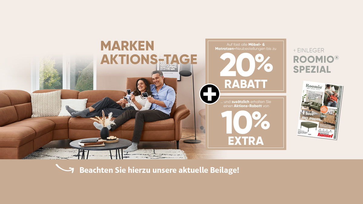 Ein lächelndes Paar sitzt mit Getränken in der Hand auf einem braunen Sofa in einem modernen Wohnzimmer; rechts sind die Verkaufsdetails zu sehen.