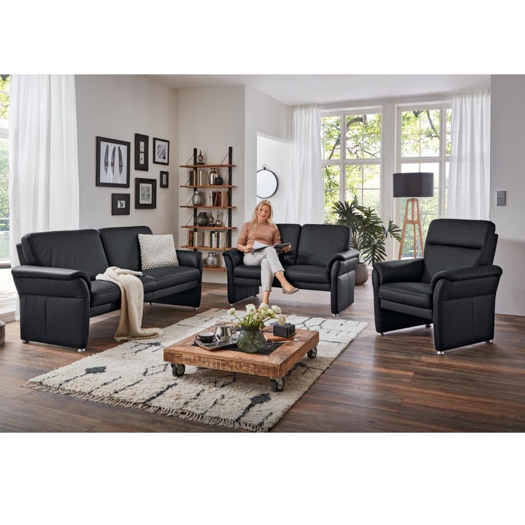 Eine Frau liest auf dem Sofa „Elemente aus Polstergarnitur Modell Bornholm II“ von Steinpol Polsteria in einem modernen, gemütlichen Wohnzimmer.