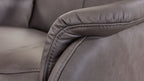 Nahaufnahme eines grauen Ledersofas, das den gepolsterten Armlehnenbereich mit sichtbarer Naht und leicht geprägter Oberfläche zeigt.