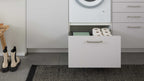 Ein offenes, graues Schubladenmöbel zeigt darin mehrere Rollen Toilettenpapier und einen grünen Ordner, daneben steht ein kleiner Holzregal.
