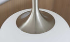 Die Detailaufnahme zeigt die Basis einer Lampe mit einem glänzenden, metallischen Fuß und einem weißen, runden Lampenschirm.