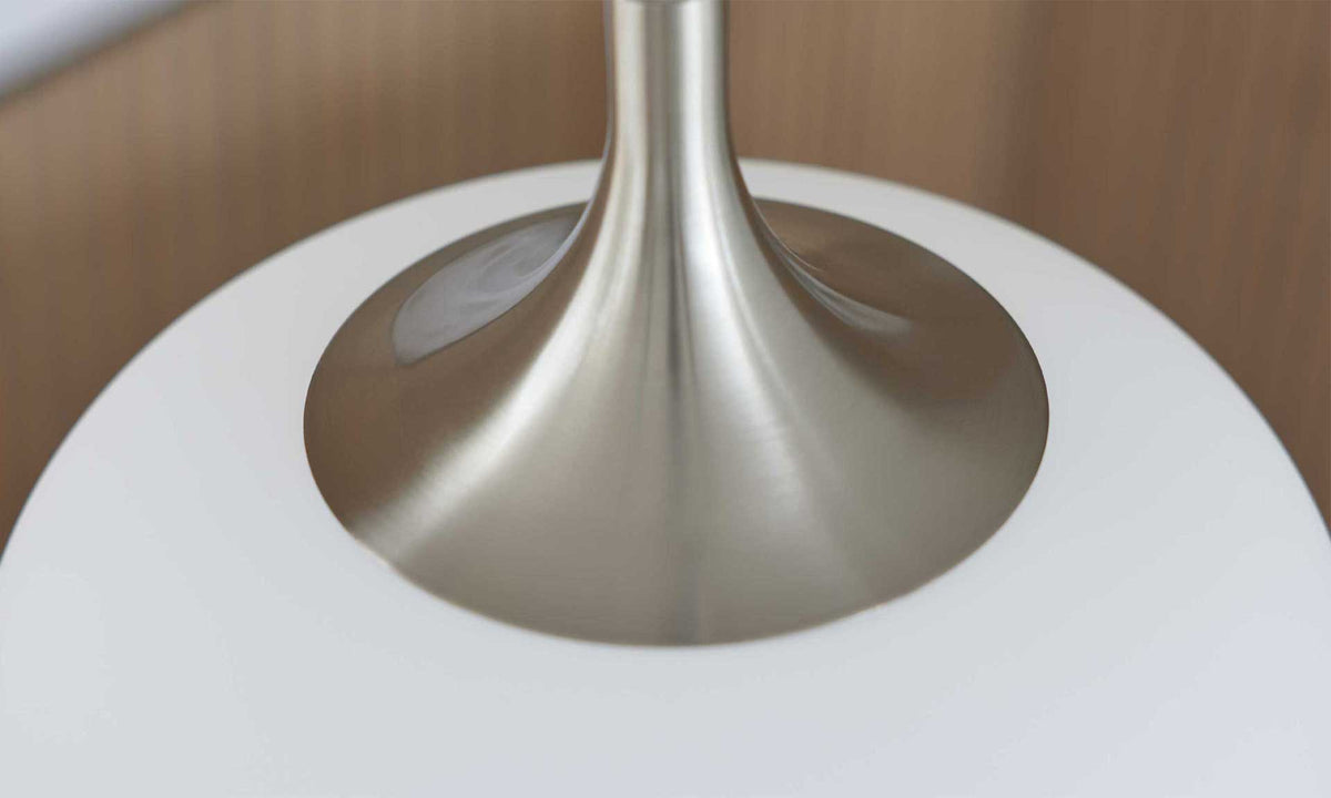 Die Detailaufnahme zeigt die Basis einer Lampe mit einem glänzenden, metallischen Fuß und einem weißen, runden Lampenschirm.