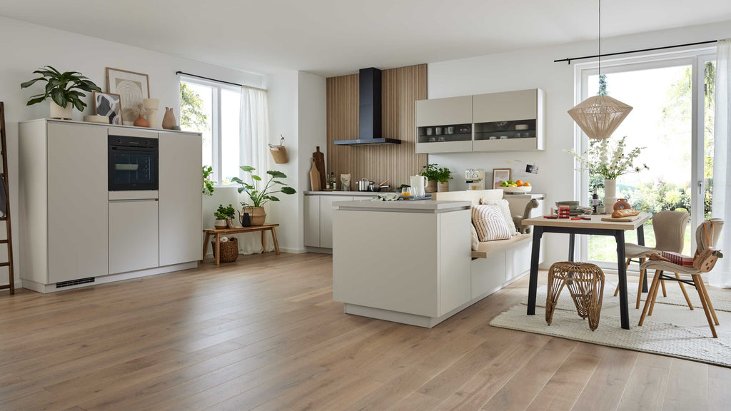 Moderne Küchenzeile mit einem hellen Unterschrank, einem Holzregal, einem Esstisch mit Stühlen und Pflanzen im Hintergrund.