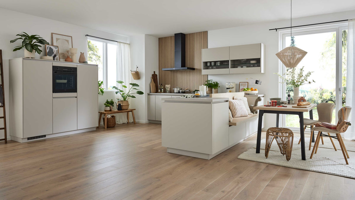 Moderne Küchenzeile mit einem hellen Unterschrank, einem Holzregal, einem Esstisch mit Stühlen und Pflanzen im Hintergrund.
