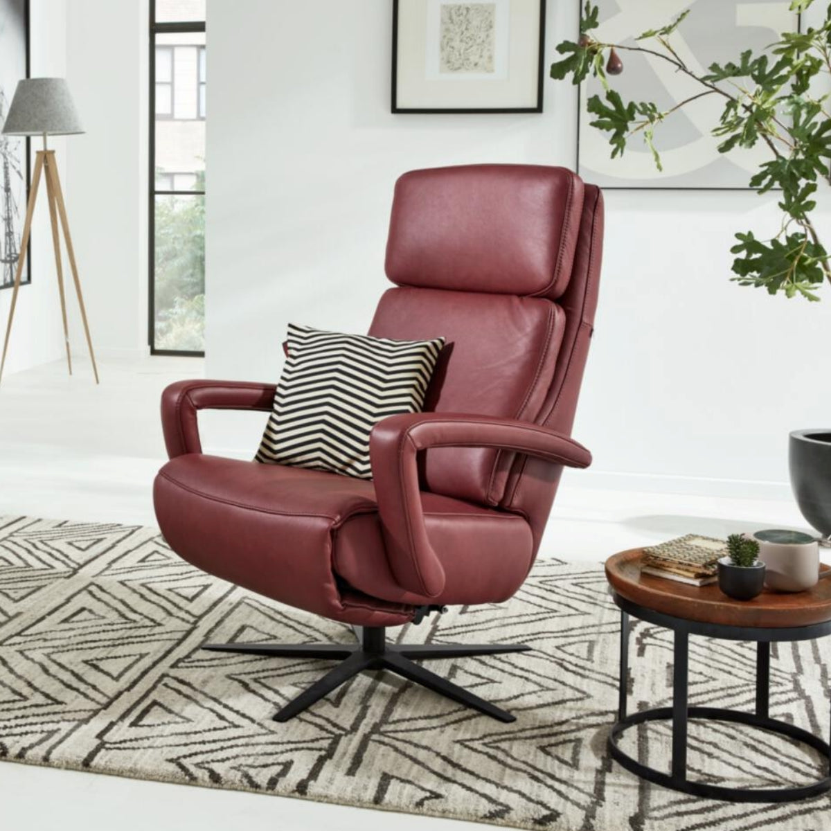 Ein roter HUKLA® | IL-Sessel aus der Interliving-Serie 4541 auf einem gemusterten Teppich mit einem gestreiften Kissen in einem modernen Wohnzimmer.