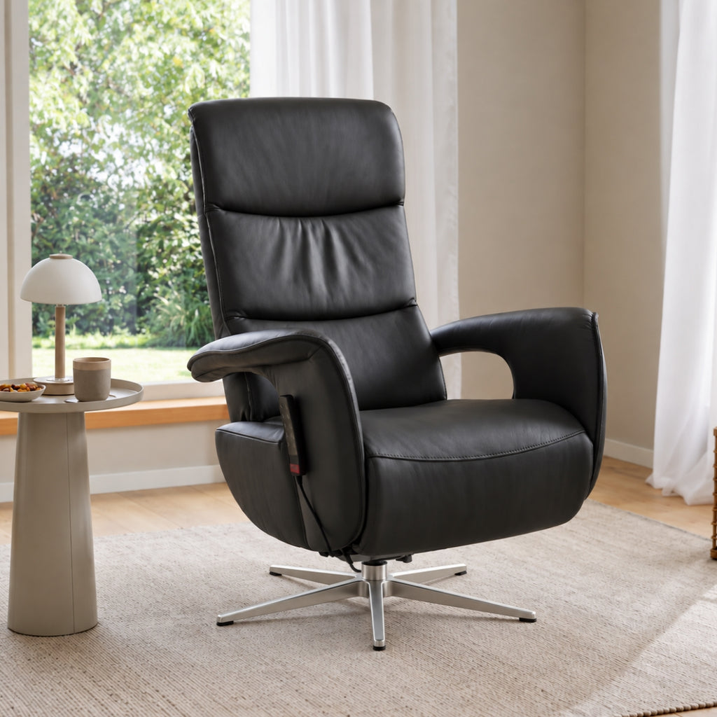 Ein Relaxsessel der Interliving-Serie 4545 von HUKLA® | IL aus Glattleder steht neben einem runden Tisch auf einem Teppich in einem hellen Raum.