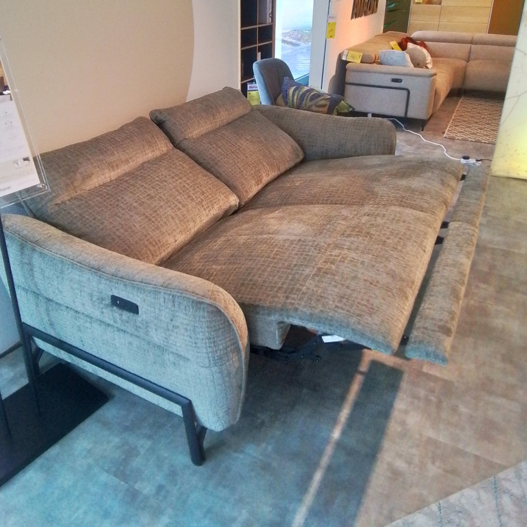 Ein 3-Sitzer-Sofa „Habufa Valletta“ von 0176 ist in einem modernen Ausstellungsraum neben einem braunen Komfortsofa mit Liegefunktion ausgestellt.