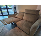 Habufa 3-Sitzer-Sofa „Valletta“ von 0176, brauner Liegesessel mit ausgeklappter Fußstütze, abgebildet in einem Innenraum vor großen Fenstern.