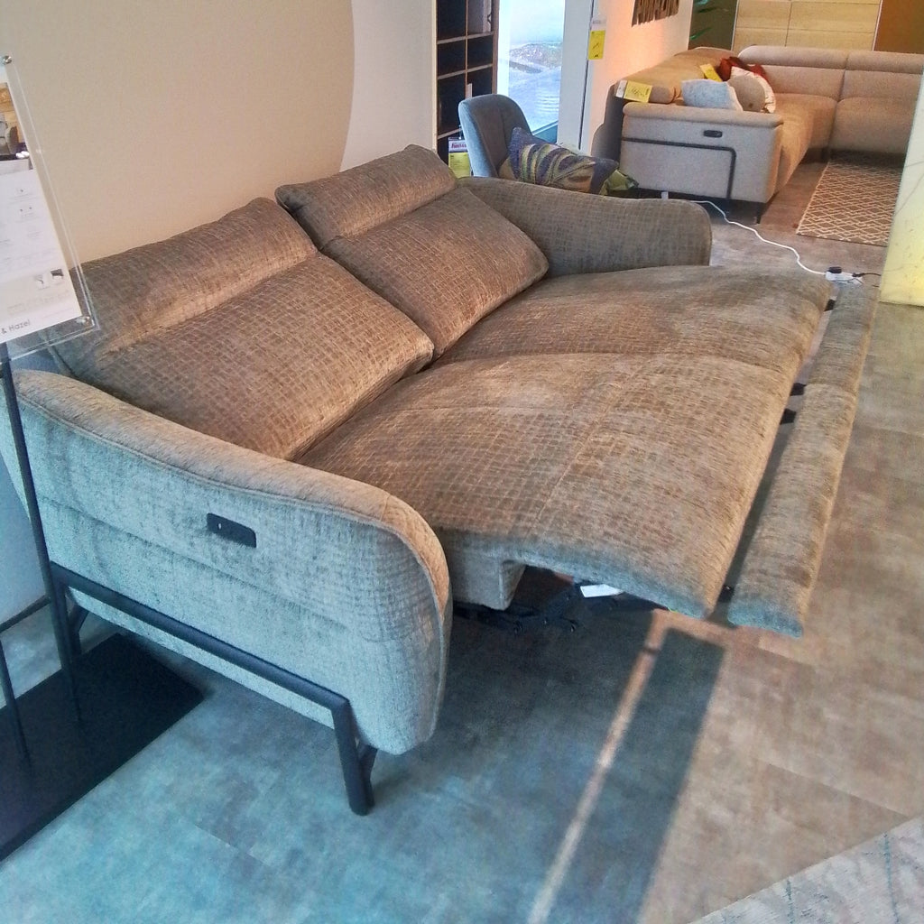 Ein graues 3-Sitzer-Sofa „Habufa 49553 Valletta“ von 0176 lässt sich zu einem Bett ausklappen; dahinter steht im Ausstellungsraum ein weiteres Sofa.