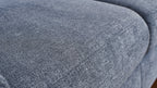 Nahaufnahme einer blauen Polsteroberfläche mit weichem Textil und einer strukturierten, leicht schimmernden Oberfläche.