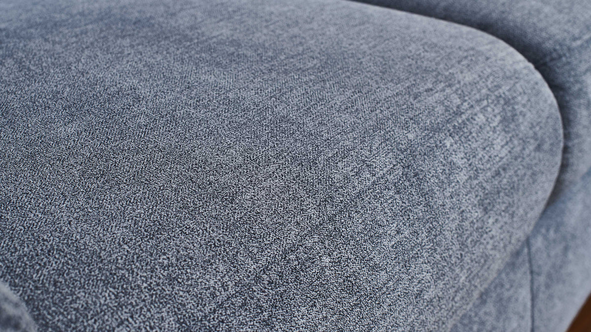 Nahaufnahme einer blauen Polsteroberfläche mit weichem Textil und einer strukturierten, leicht schimmernden Oberfläche.
