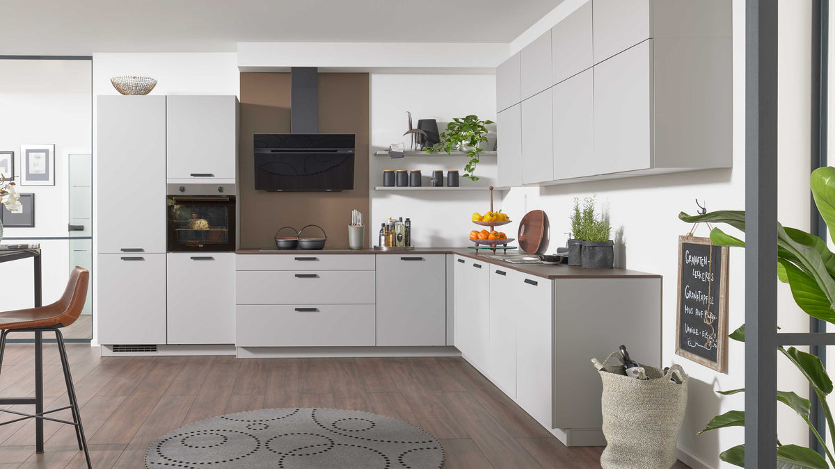 Moderne Küchenzeile in Grau mit Holzarbeitsfläche, ausgestattet mit einem Herd, Backofen, Dunstabzugshaube und Regalen für Küchenaccessoires.