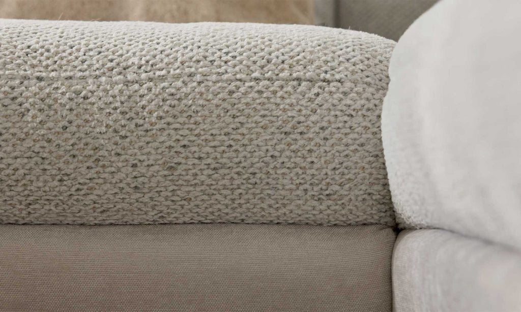 Die Nahaufnahme zeigt die Struktur eines hellen Sofa-Armrests mit einer grob gewebten Oberfläche und einem glatteren untersten Bereich.