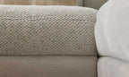 Die Nahaufnahme zeigt die Struktur eines hellen Sofa-Armrests mit einer grob gewebten Oberfläche und einem glatteren untersten Bereich.