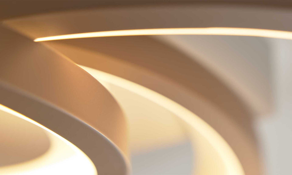 Eine moderne Lampe mit geschwungenen, cremefarbenen Elementen, die von einer warmen Lichtquelle beleuchtet werden.