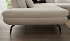 Die Unterseite eines Sofa-Sitzkissens mit einer hellen, strukturierten Polsterung und schmalen, schwarzen Metallbeinen.