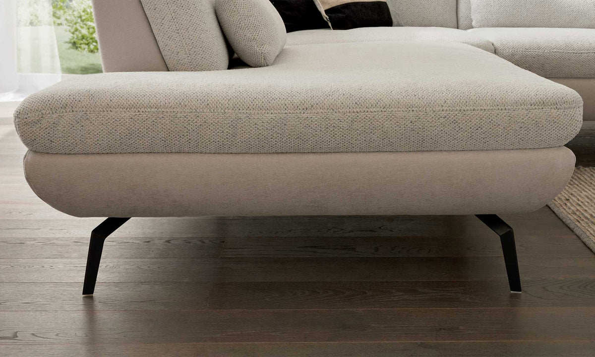 Die Unterseite eines Sofa-Sitzkissens mit einer hellen, strukturierten Polsterung und schmalen, schwarzen Metallbeinen.