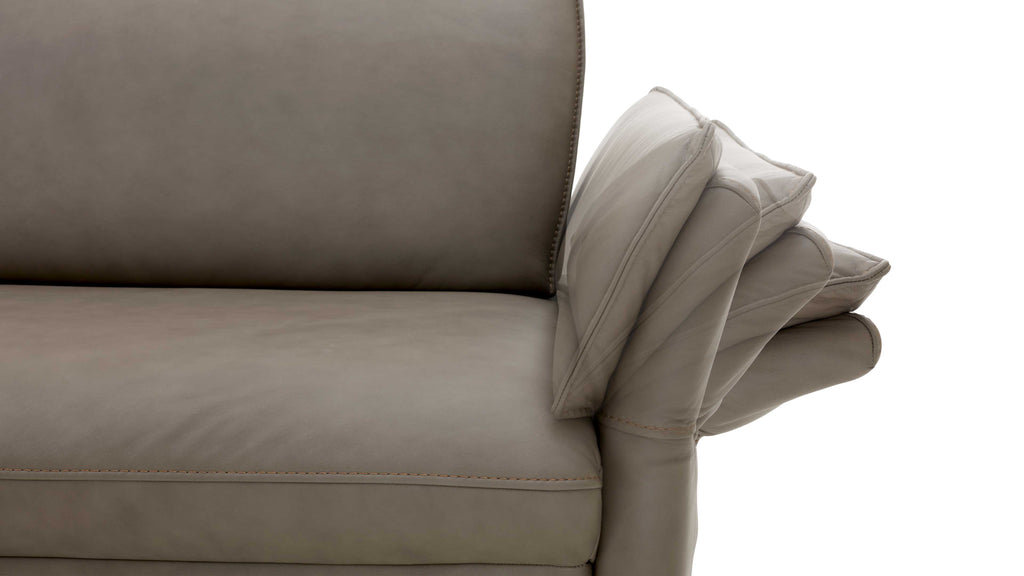 Eine graue Sofa-Ecke mit einer leicht ausgeformten Rückenlehne und einer abgerundeten Armlehne, die eine geometrische Struktur aufweist.