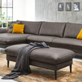 Modernes Wohnzimmer mit grauem Ecksofa, HUKLA® XXL-Hocker, gelben Kissen, einer Überwurfdecke und Wandbildern.