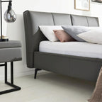 HUKLA® Interliving Serie 1416 Lederpolsterbett 180 × 200 cm in Anthrazit mit Nachttisch und Lampe.