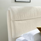 Nahaufnahme des HUKLA® Interliving Serie 1416 Polsterbettgestells mit weißer Bettwäsche und einem goldenen Kissen in einem hellen Raum.