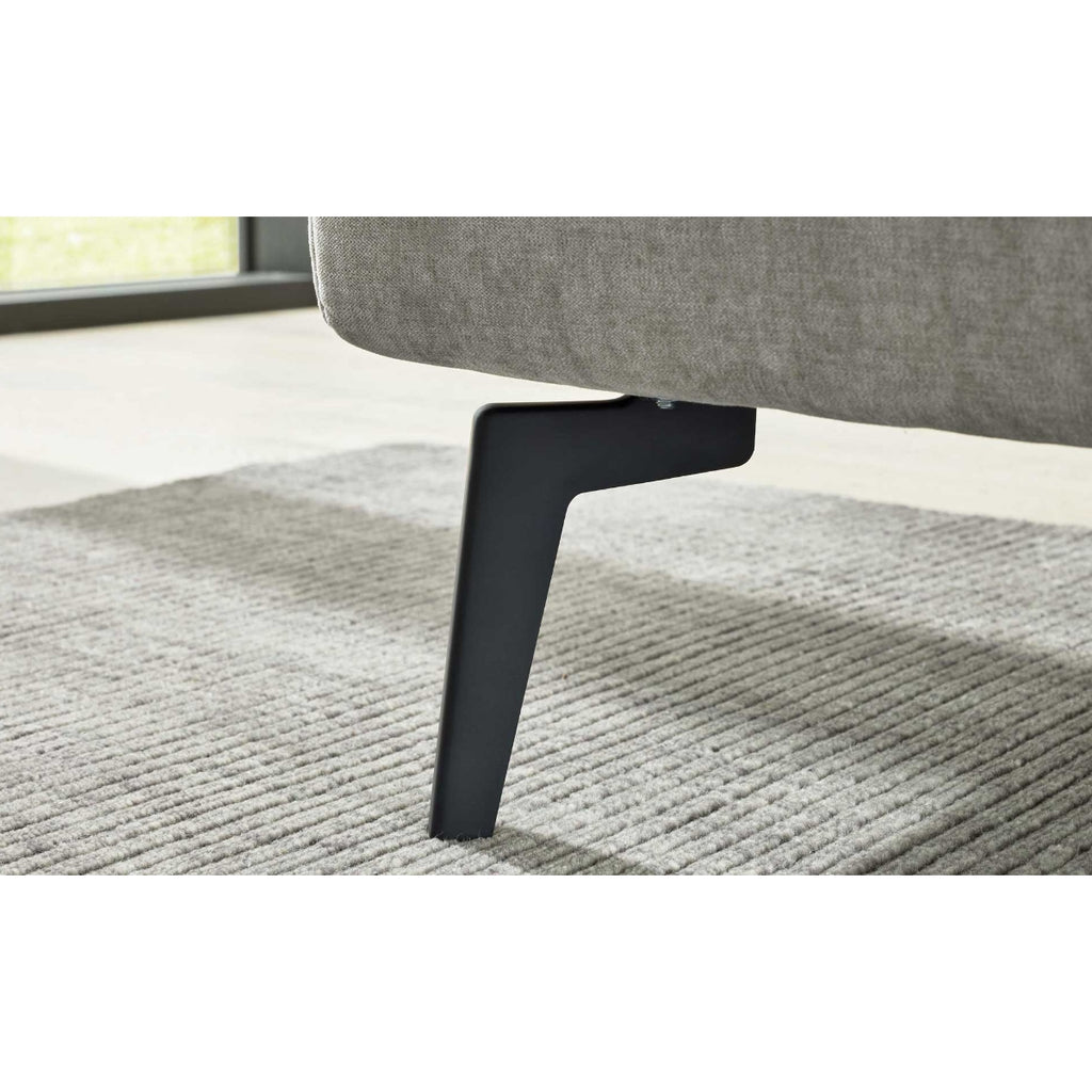 Schwarzes Metallsofabein auf grauem Teppich unter einem HUKLA® Interliving Serie 1416 Polsterbettgestell, Balu Silver, 180 x 200 cm.