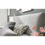 HUKLA® Interliving Serie 1416 Polsterbett 180 x 200 cm, Balu Silver mit Kissen und rosa Blumen vor einer grünen Wand.