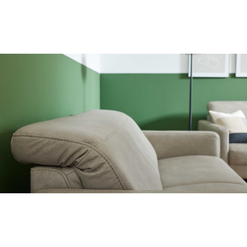 HUKLA® | IL Interliving Serie 4065 2,5-Sitzer aus Leder, Farbe „Cloudy Gravel“, mit Kopfstützen in einem modernen Raum vor einer grünen Wand.