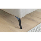Nahaufnahme eines schwarzen Metallfußes W008-M01, Sofa „Interliving Serie 4065“ von HUKLA® | IL, auf hellem Holzboden mit beigem Teppich.