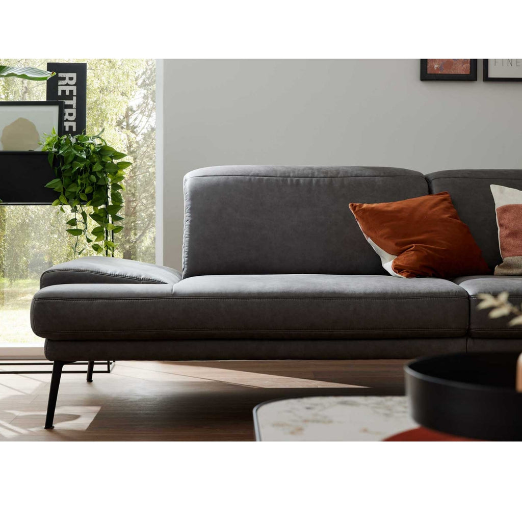 Ein dunkelgraues Zweisitzer-Sofa von Steinpol Polsteria | IL 4460 mit orangefarbenen Kissen belebt das moderne Wohnzimmer.
