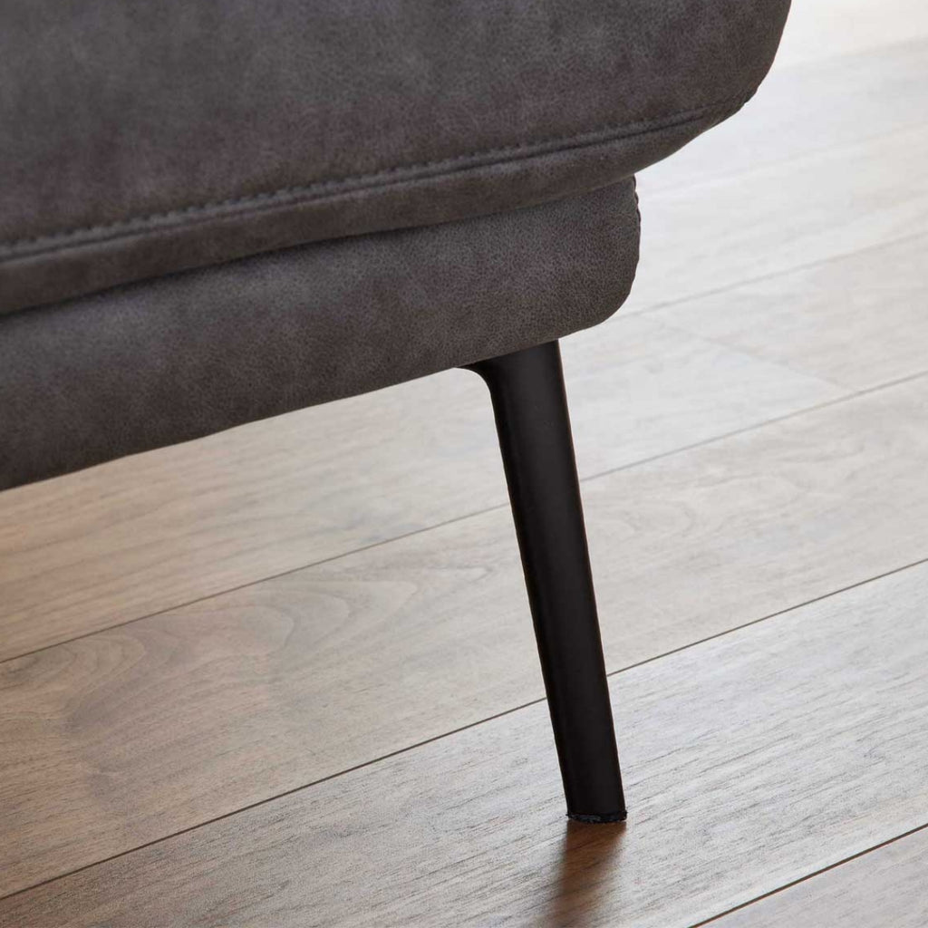 Nahaufnahme eines schwarzen Metallfußes des Zweisitzer-Sofas „Interliving 4460“ von Steinpol Polsteria; oben ist der dunkelgraue Stoff zu sehen.