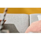 Nahaufnahme des Ecksofas „IL“ von Steinpol Polsteria, Modell Interliving 4460, mit silbernem Stoffbezug, schwarzen, runden Metallfüßen sowie rosa und weißen Kissen.