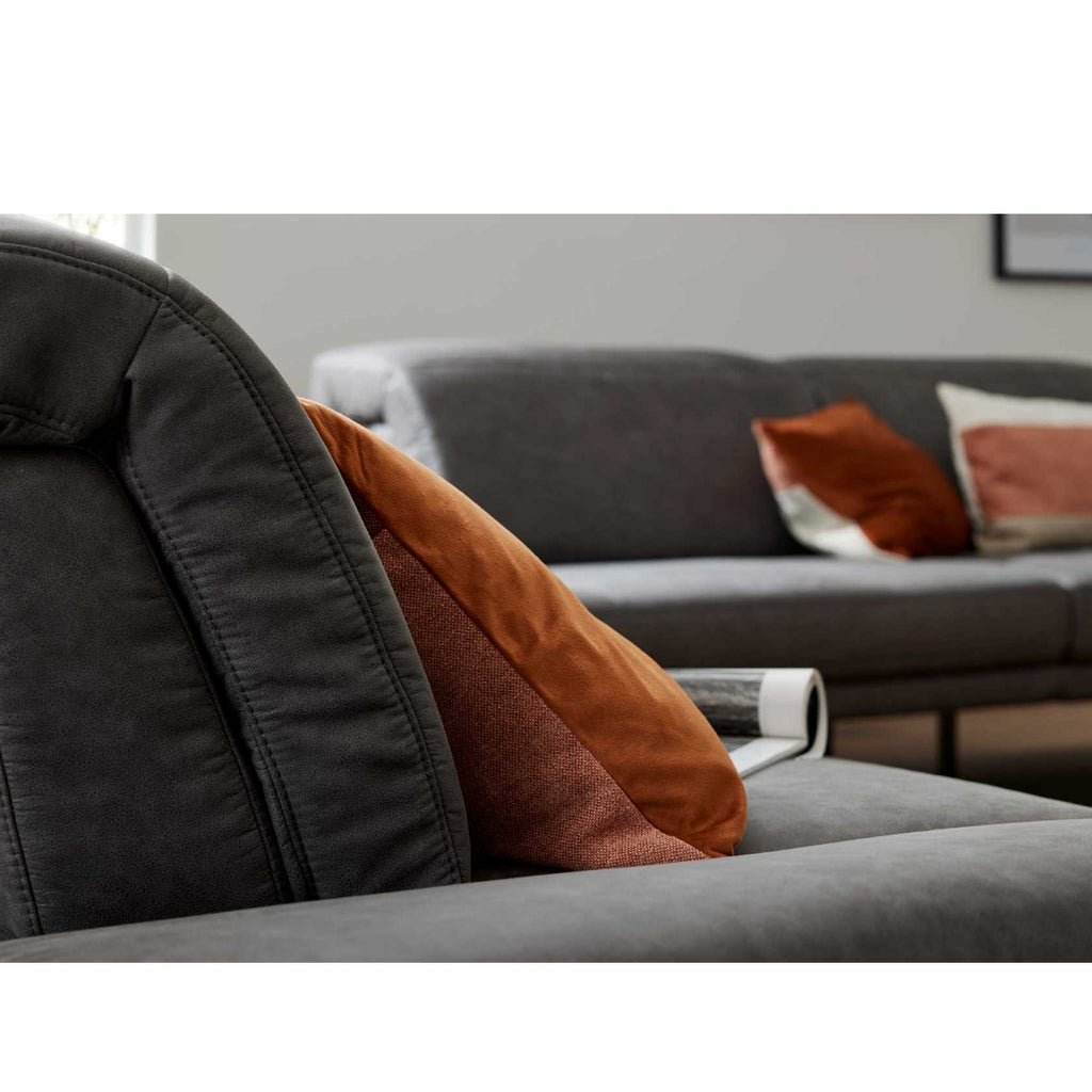 Nahaufnahme eines Zweisitzer-Sofas „Interliving 4460“ in Dunkelgrau von Steinpol Polsteria | IL mit orangefarbenen und roten Kissen.